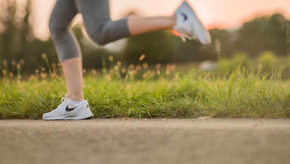 Corredor urbano com tênis esportivos em movimento na calçada da cidade, representando o universo de ação que "Just Do It" convocou desde 1988.