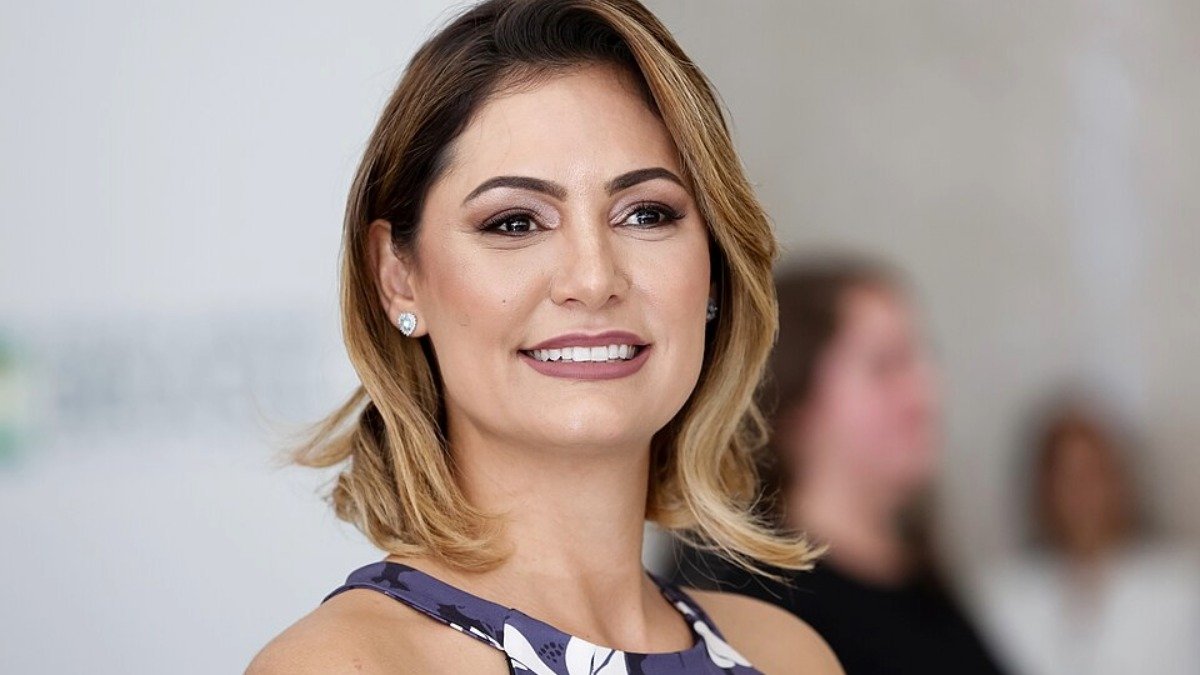 Retrato de Michelle Bolsonaro em evento oficial, usado como capa do artigo sobre a crise com Flávio Bolsonaro e a saída da presidência do PL Mulher.