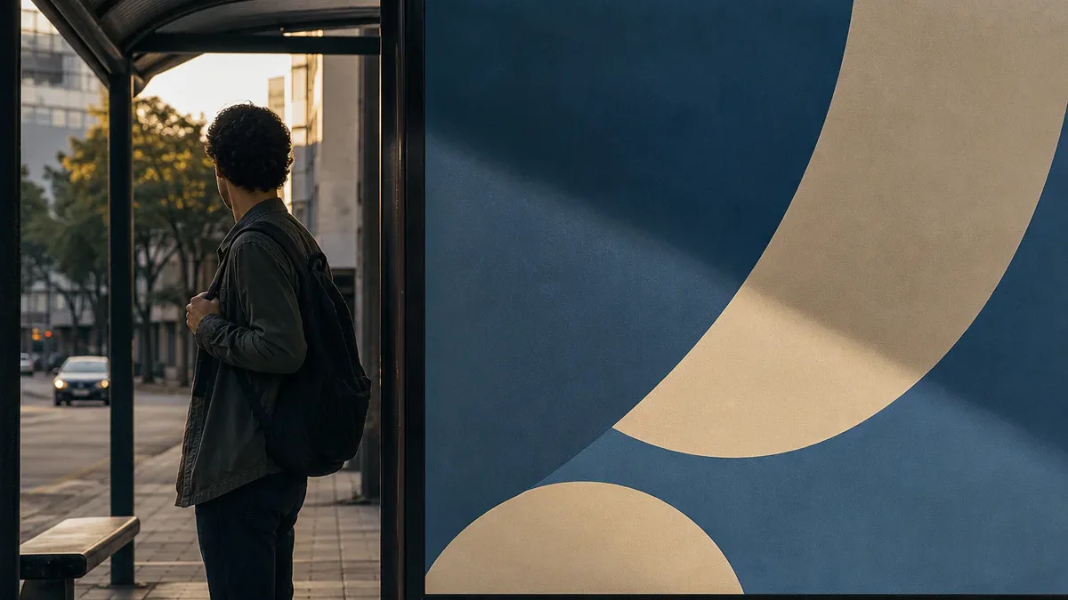 Pessoa em um ponto de ônibus desvia o olhar de um painel publicitário sem texto.